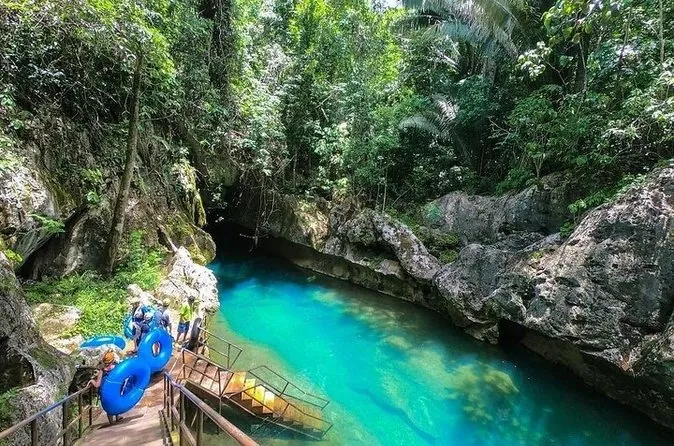 A turquoise river pool in a jungle gorge with inner tubes by a wooden walkway