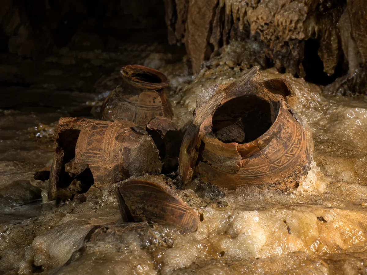 Ancient Maya ceramic pots cemented to a sparkling cave floor in a headlamp beam